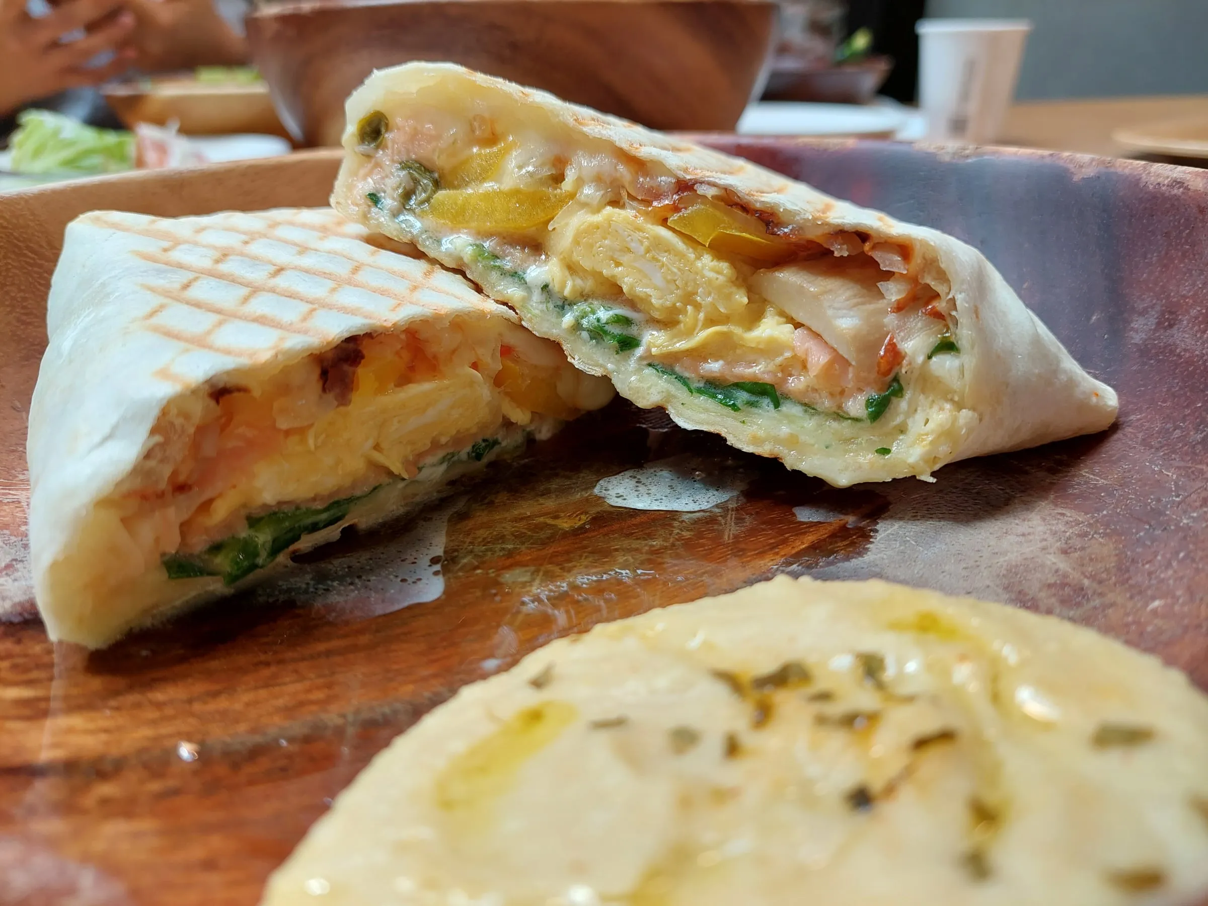 A grilled wrap cut open, filled with vegetables and fillings