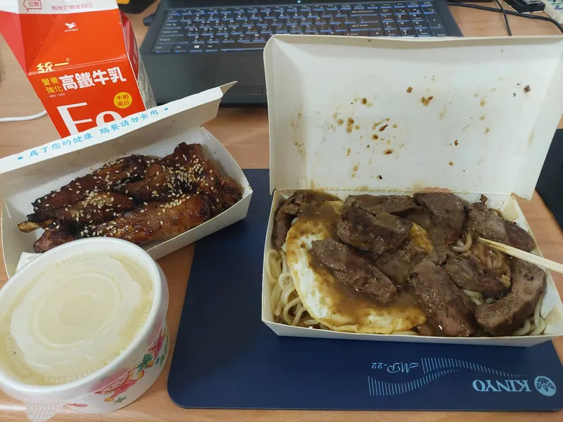Grilled ribs, beef noodles and a carton of milk on an office desk