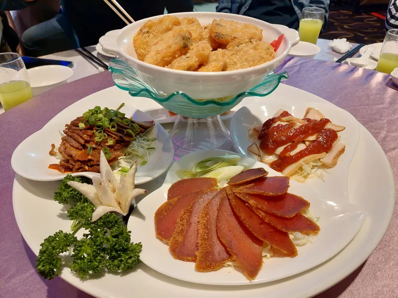 A cold platter on a round banquet table, with assorted sliced meats and fried bites