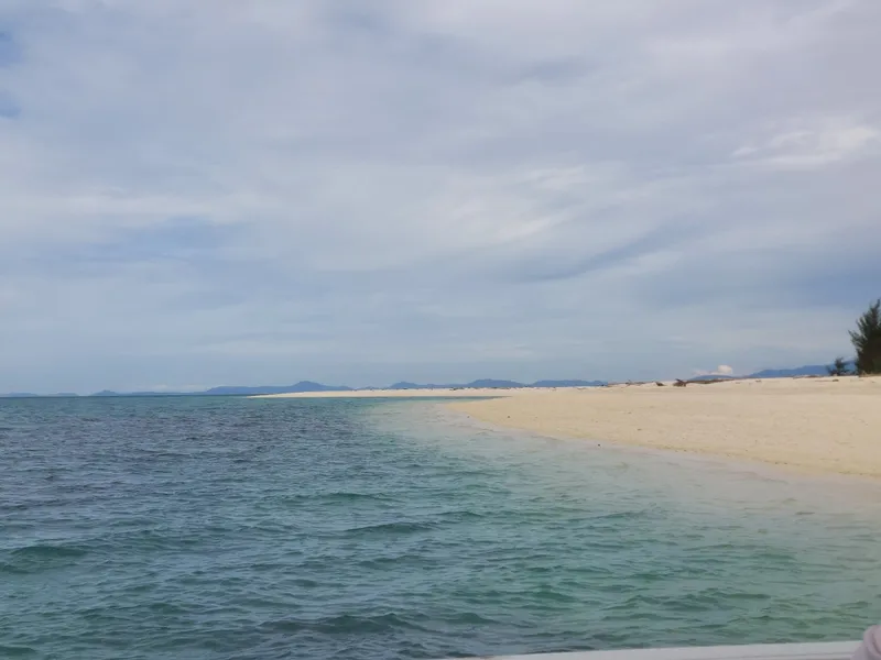 A strip of white sand stretching into a calm sea