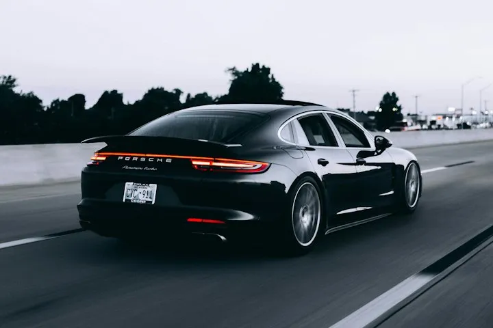 Dark Porsche Panamera Turbo driving on a highway at twilight, rear three-quarter view with motion blur