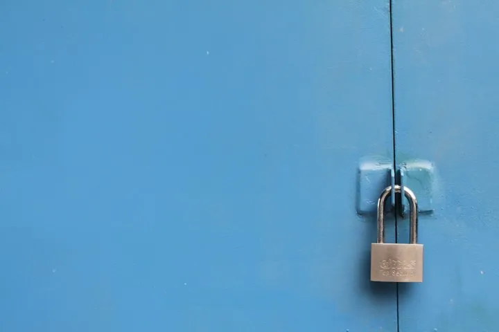 Silver padlock fastened through hasps on a light blue painted metal door