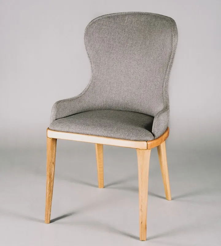Studio photo of a modern grey upholstered chair with a high back and light wooden tapered legs