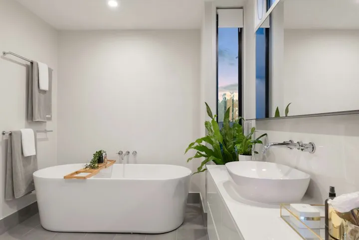 Bright modern bathroom with a white freestanding oval tub, vessel sink, and a large indoor plant